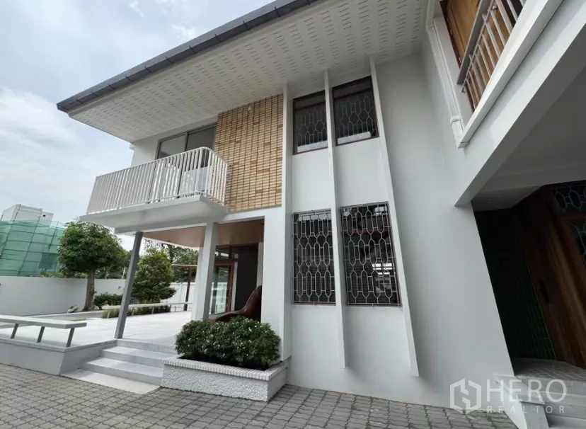 独立式住宅 出租在Watthana, Bangkok - 白色两层住宅侧立面，设阳台与大窗。
