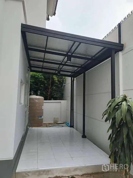 独立式住宅 出租在Bang Kapi, Bangkok - 带金属结构顶棚的铺砖露台或车棚，旁有水箱。