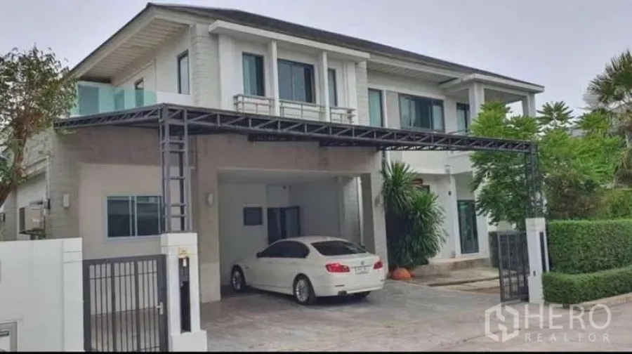独立式住宅 出租在Mueang Nonthaburi, Nonthaburi - 正面外观另一角度，两层独栋别墅配车棚与金属大门。
