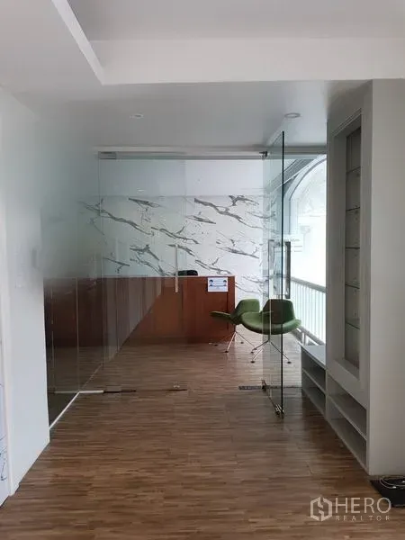 Retail Space for rent in Khlong Toei, Bangkok - Glass-partitioned reception with marble accent wall, wood floors and a green chair in Phra Khanong retail space.