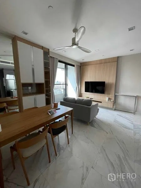 Condominium for rent or sale in Bang Rak, Bangkok - Living room with TV feature wall, dining table, and access to the balcony.