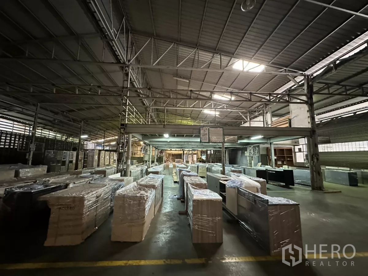 Warehouse for rent in Yan Nawa, Bangkok - Central work area beneath mezzanine with wrapped cabinets and benches.