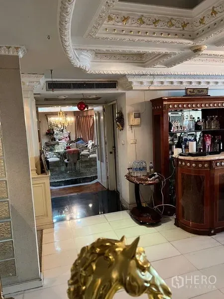 Condominium for sale in Khlong Toei, Bangkok - Hallway connecting living area and dining room featuring a wooden bar and detailed ceiling mouldings.