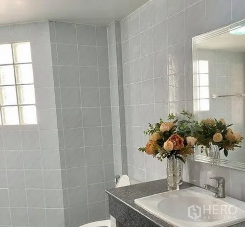 Home Office for rent in Khlong Toei, Bangkok - Tiled bathroom with a countertop sink, mirror and window bringing in natural light.