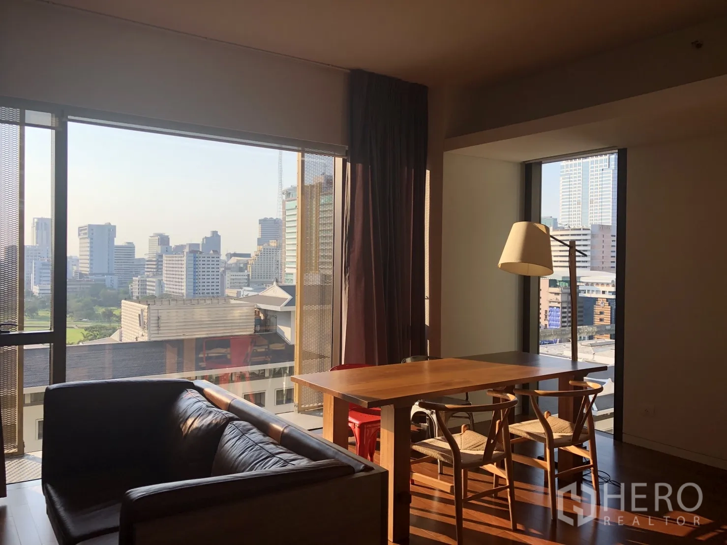 Condominium for rent in Pathum Wan, Bangkok - Dining corner beside large picture windows offering Bangkok skyline and Royal Bangkok Sports Club greenery.