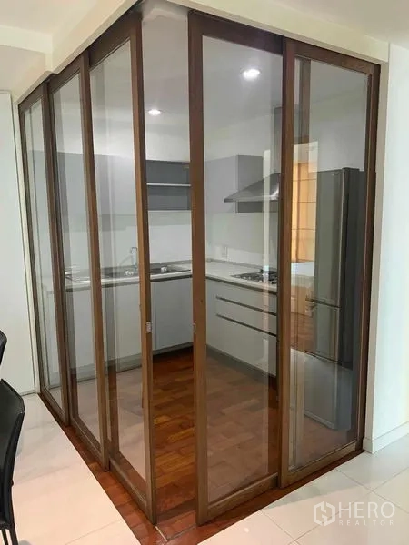 Condominium for rent or sale in Khlong Toei, Bangkok - Folding glass doors enclosing a modern gray kitchen with appliances.