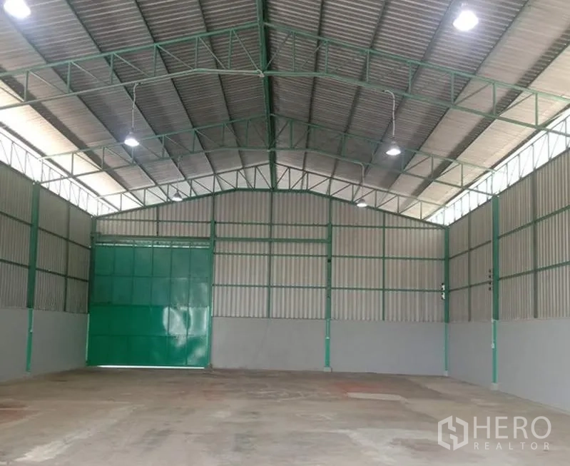 คลังสินค้า ให้เช่าในBang Bua Thong, Nonthaburi - พื้นที่เก็บสินค้าโล่ง ประตูบานเลื่อนสีเขียว ไฟไฮเบย์สว่าง