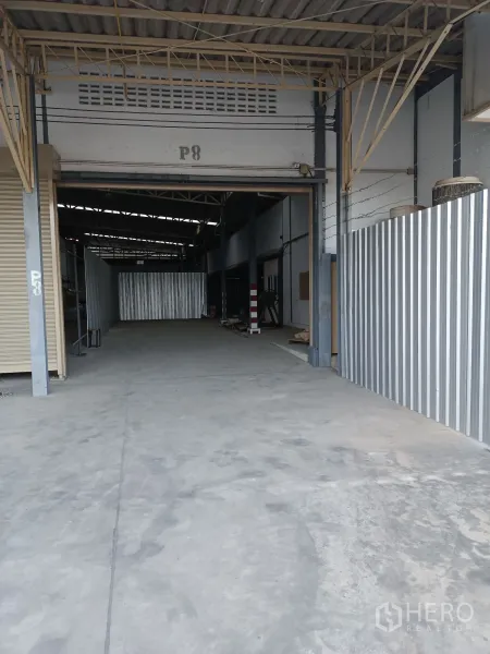 Warehouse for rent in Suan Luang, Bangkok - Covered driveway and rolling-shutter entrance to a high-ceiling warehouse in Suan Luang.