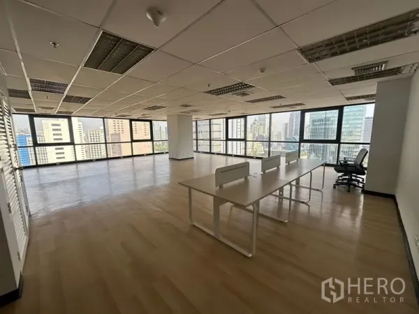 Office Space for rent in Bang Rak, Bangkok - Bright open-plan corner office with wood floors and wraparound windows overlooking the Bangkok skyline.