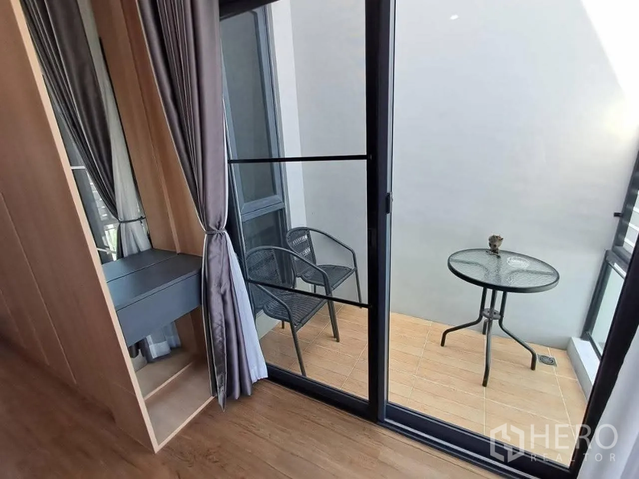 Townhouse for rent in Bang Kapi, Bangkok - Small balcony with round glass table and two chairs behind sliding doors.