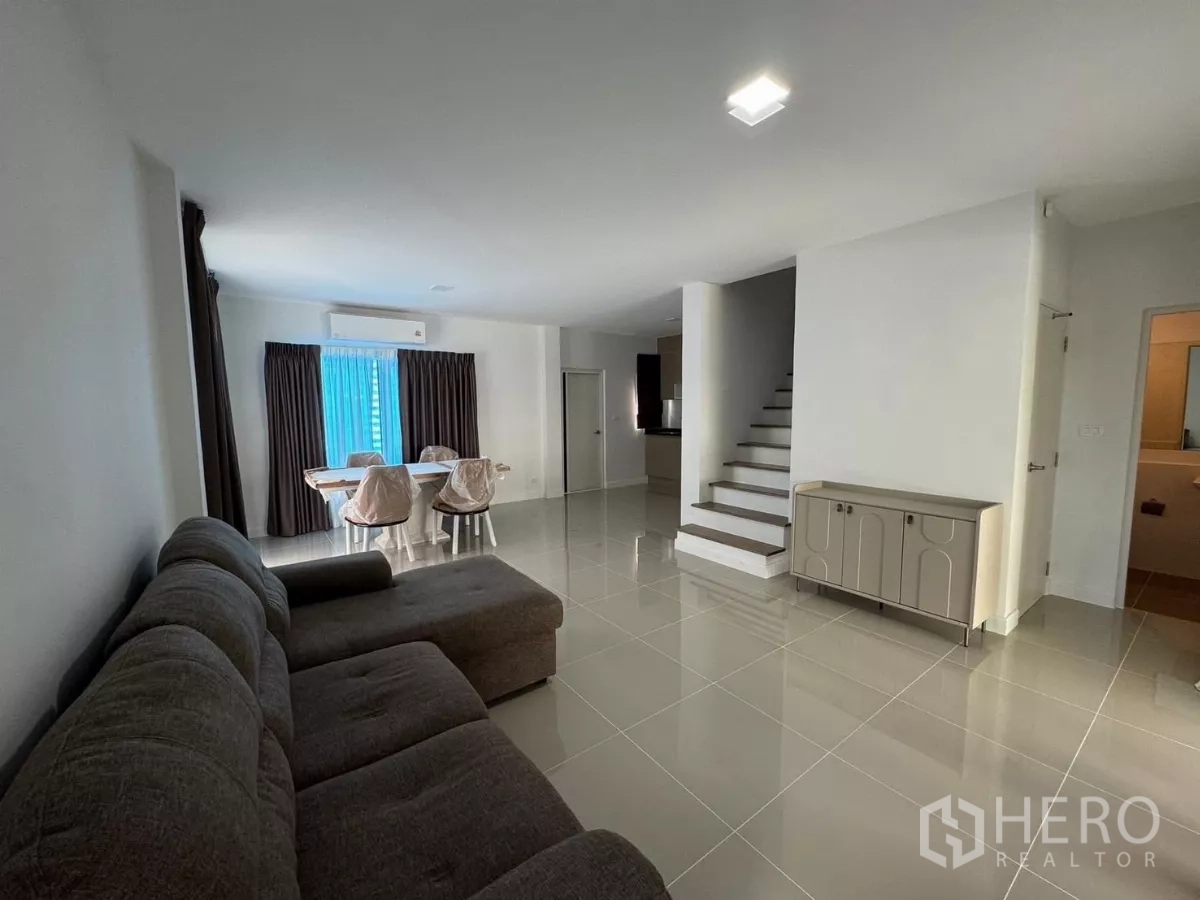Detached House for rent in Bang Phli, Samut Prakan - Open-plan living and dining area with sofa, tiled floors, air-conditioning and curtains.