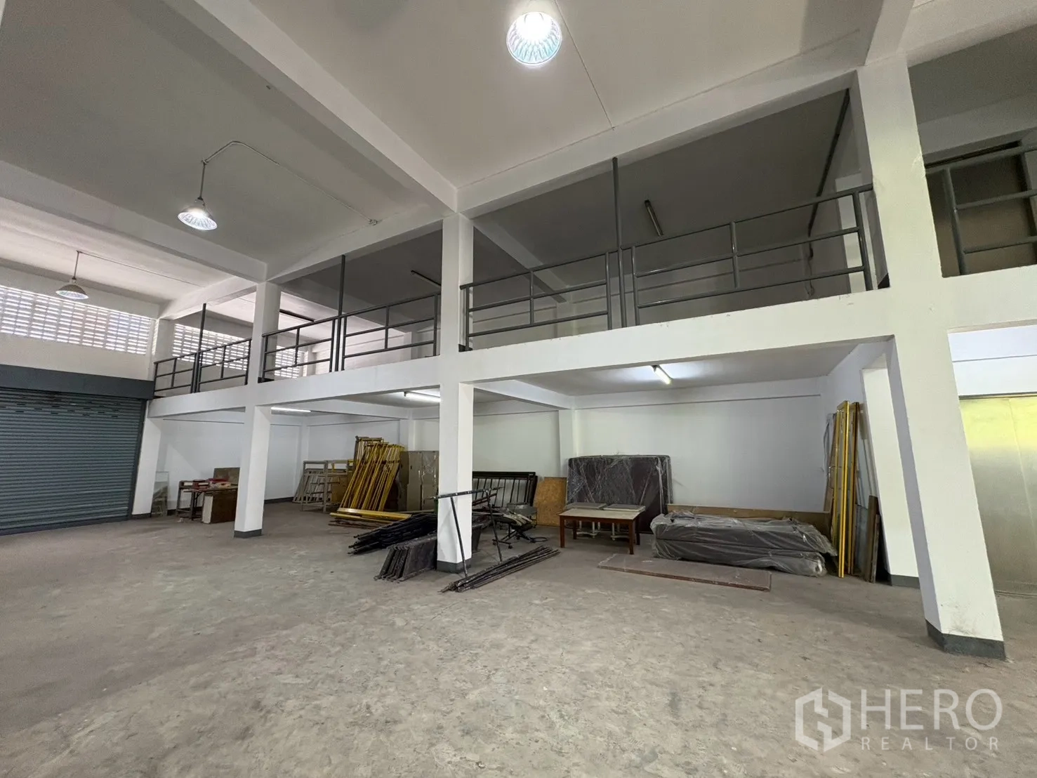 Warehouse for rent in Bang Na, Bangkok - Ground-level view showing mezzanine platforms and a roller shutter.