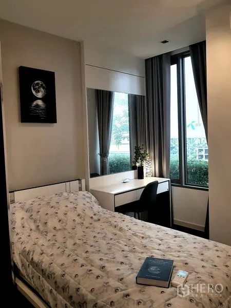 Condominium for rent in Sathon, Bangkok - Cozy bedroom with single bed, study desk, tall windows and garden view.