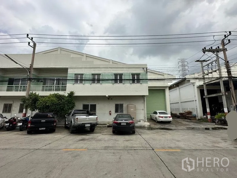 Factory for rent in Khlong Luang, Pathum Thani - Front elevation of the factory with balcony, parking spaces and oversized loading door.