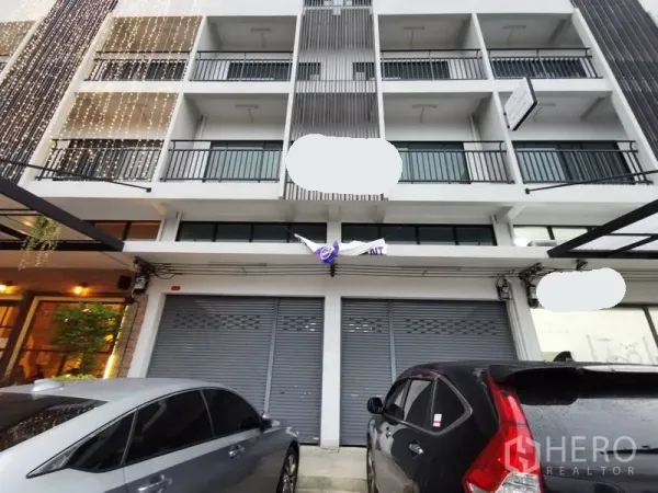 带办公室的家 出租在Suan Luang, Bangkok - 多层居家办公楼外立面，连排阳台与卷闸门门面，前方可停车