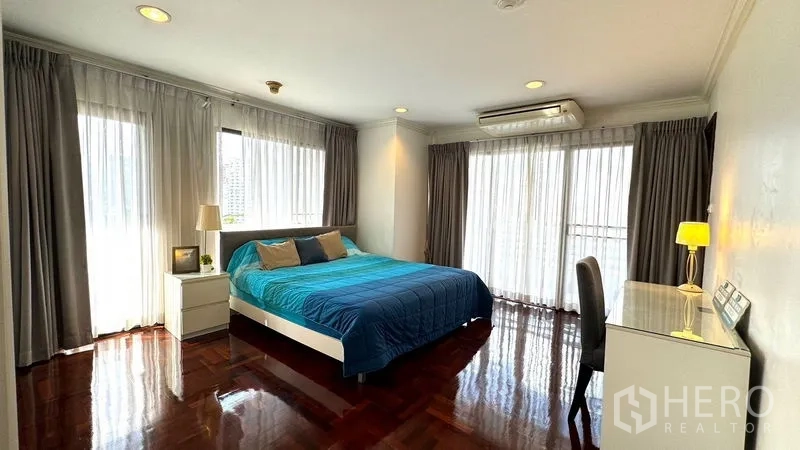 Condominium for rent or sale in Watthana, Bangkok - Primary bedroom with glossy wooden floors and sliding glass doors to a balcony.
