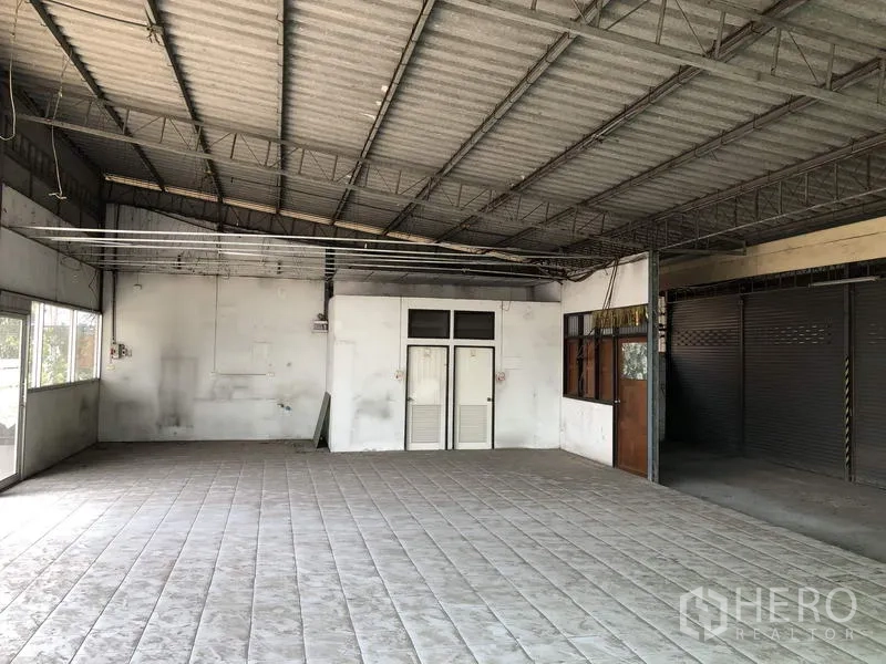货栈 出租在Khlong Luang, Pathum Thani - 室内开放空间，铺砖地面与钢结构屋顶，带小型办公室门。