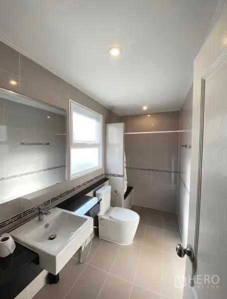 Detached House for sale in Bang Phli, Samut Prakan - Bright tiled bathroom with a window, wall-mounted sink, and modern toilet.