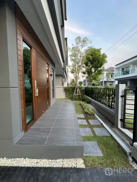 Detached House for rent in Bang Phli, Samut Prakan - Front terrace with grey tiles, small garden and metal fence.