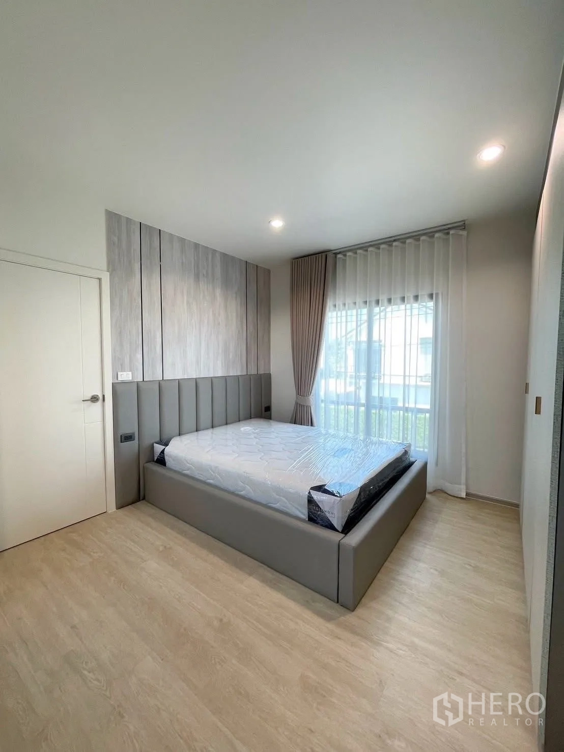 บ้านเดี่ยว for rent in Bang Phli, Samut Prakan - ห้องนอนรองพร้อมเตียงบุนวมสีเทา หน้าต่างสูงจรดเพดาน และโทนห้องเรียบหรู