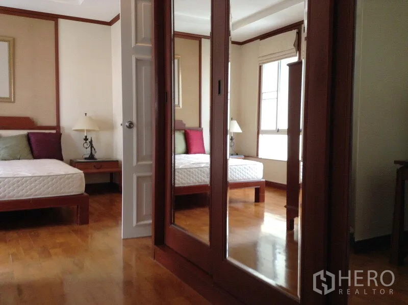 公寓 出租或出售在Watthana, Bangkok - 主卧配镜面衣柜、床头柜与木地板。