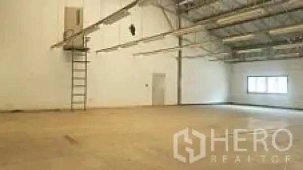 工厂 出售在Lam Luk Ka, Pathum Thani - 宽敞仓库大厅，高屋架与墙面梯子，工作区域开阔。