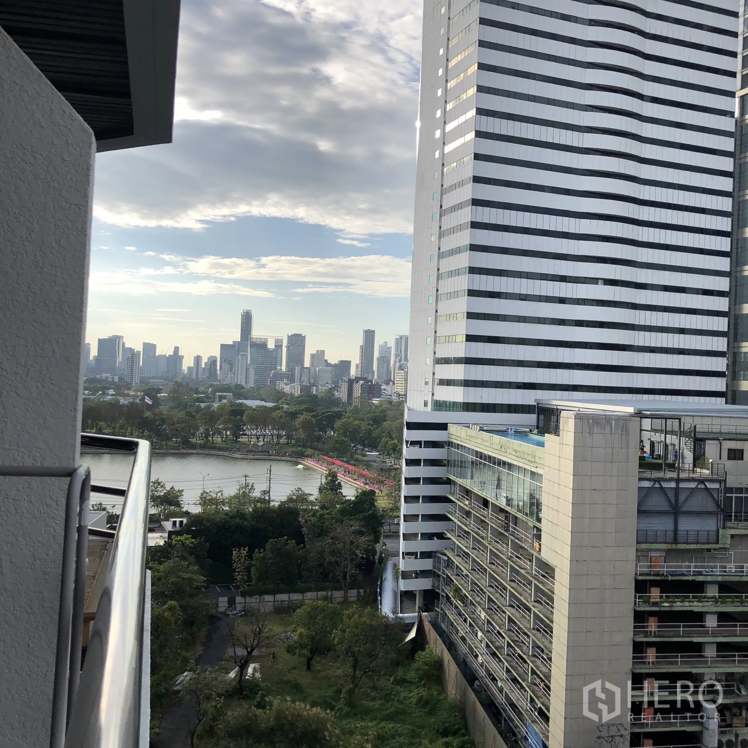 Condominium for rent in Khlong Toei, Bangkok - Balcony outlook toward Benjakitti Park lake framed by modern office towers.