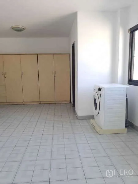 Townhouse for rent in Khlong Toei, Bangkok - Utility room with tiled floor, wardrobes and a washing machine by the window.