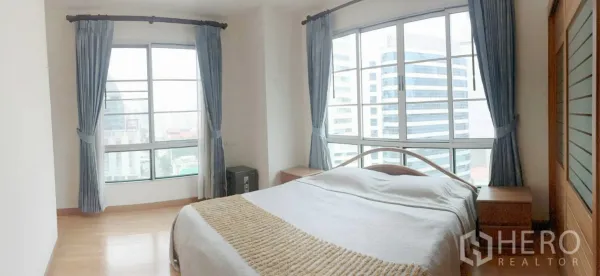 Condominium for rent in Khlong Toei, Bangkok - Bright master bedroom with large corner windows and panoramic city views.