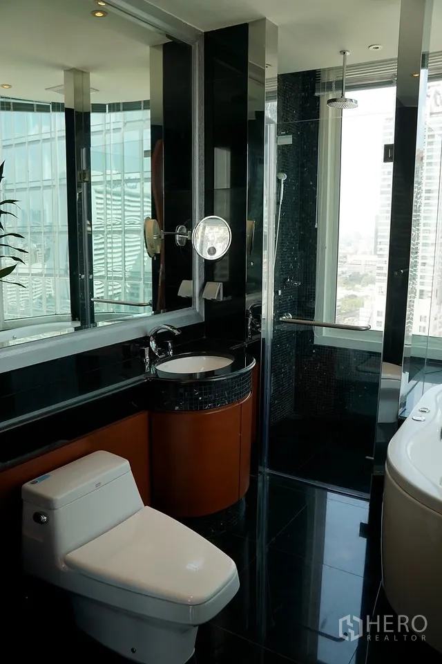 Condominium for rent in Bang Rak, Bangkok - Contemporary bathroom featuring a glass shower, soaking tub, black tiles, and city-view windows.