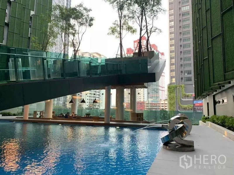 公寓 出售在Ratchathewi, Bangkok - 度假风泳池平台，可见城市天际线与上方景观步桥。