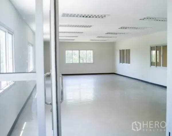 Factory for rent in Pathum Thani - Bright office room with large windows, white walls, and fluorescent ceiling lights.