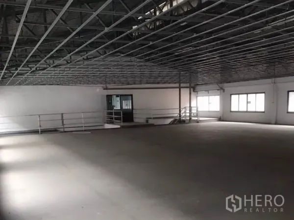 Factory for rent in Bang Bua Thong, Nonthaburi - Open upper production floor with metal truss ceiling, windows and safety railing.