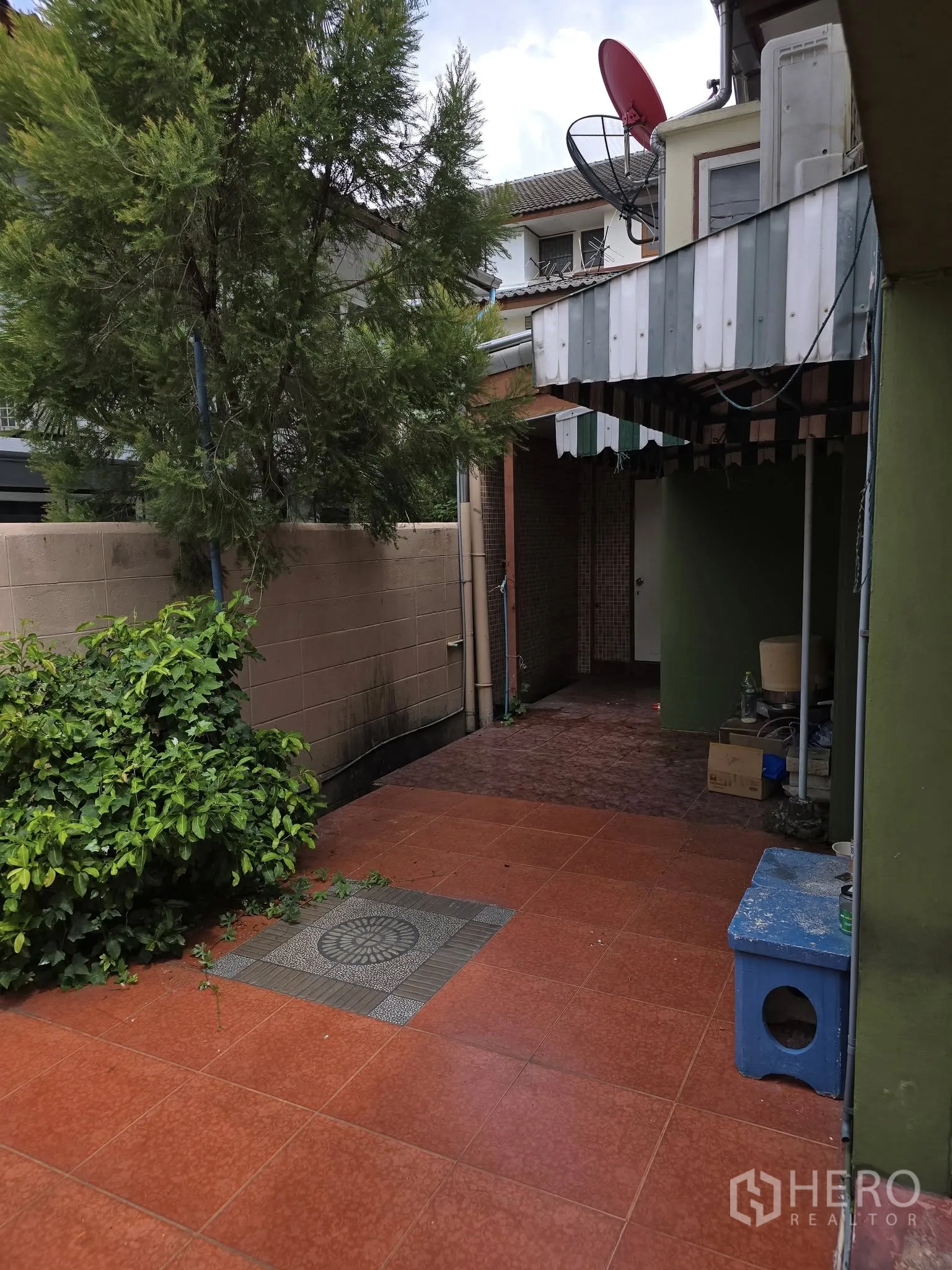 带办公室的家 出租在Wang Thonglang, Bangkok - 侧院露台，红色地砖，小树、围墙与金属雨棚