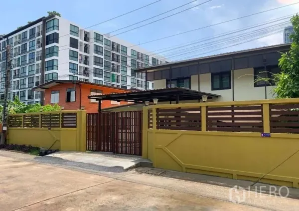 Detached House for rent or sale in Phra Khanong, Bangkok - Gated detached house with high privacy wall and condo backdrop on a quiet Phra Khanong lane.