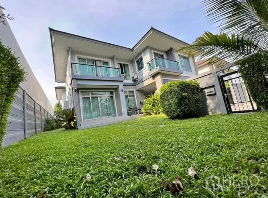 Detached House for rent or sale in Saphan Sung, Bangkok - Front yard view of the detached house with manicured hedges and a metal gate.