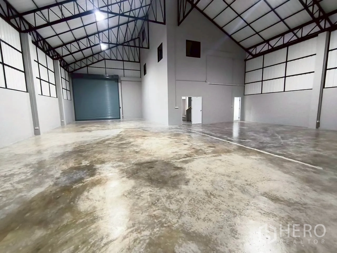 Warehouse for rent in Mueang Nonthaburi, Nonthaburi - Wide open storage space showing a roller door, multiple doors, and tall roof.