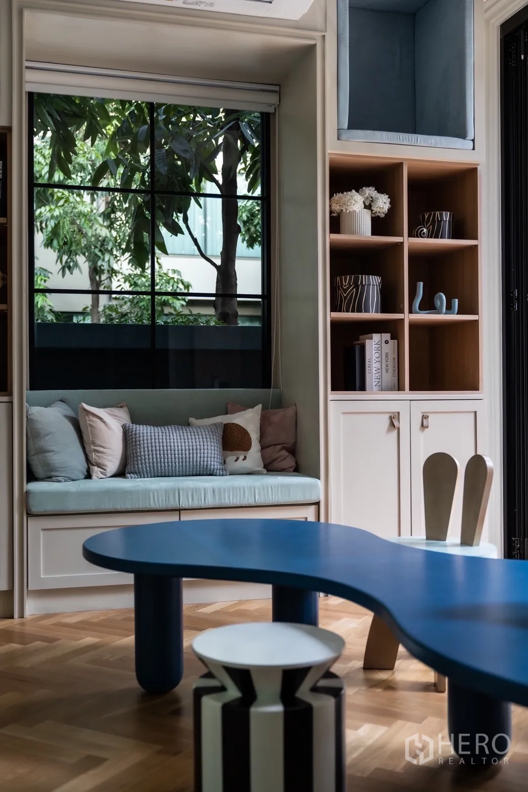 Detached House for rent or sale in Phra Khanong, Bangkok - Window seat with cushions and display shelves beside a sculptural blue table.