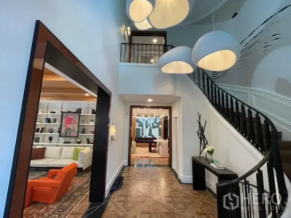 Detached House for rent or sale in Saphan Sung, Bangkok - Double-height foyer with curved staircase, statement pendant lights and parquet flooring leading to living areas.