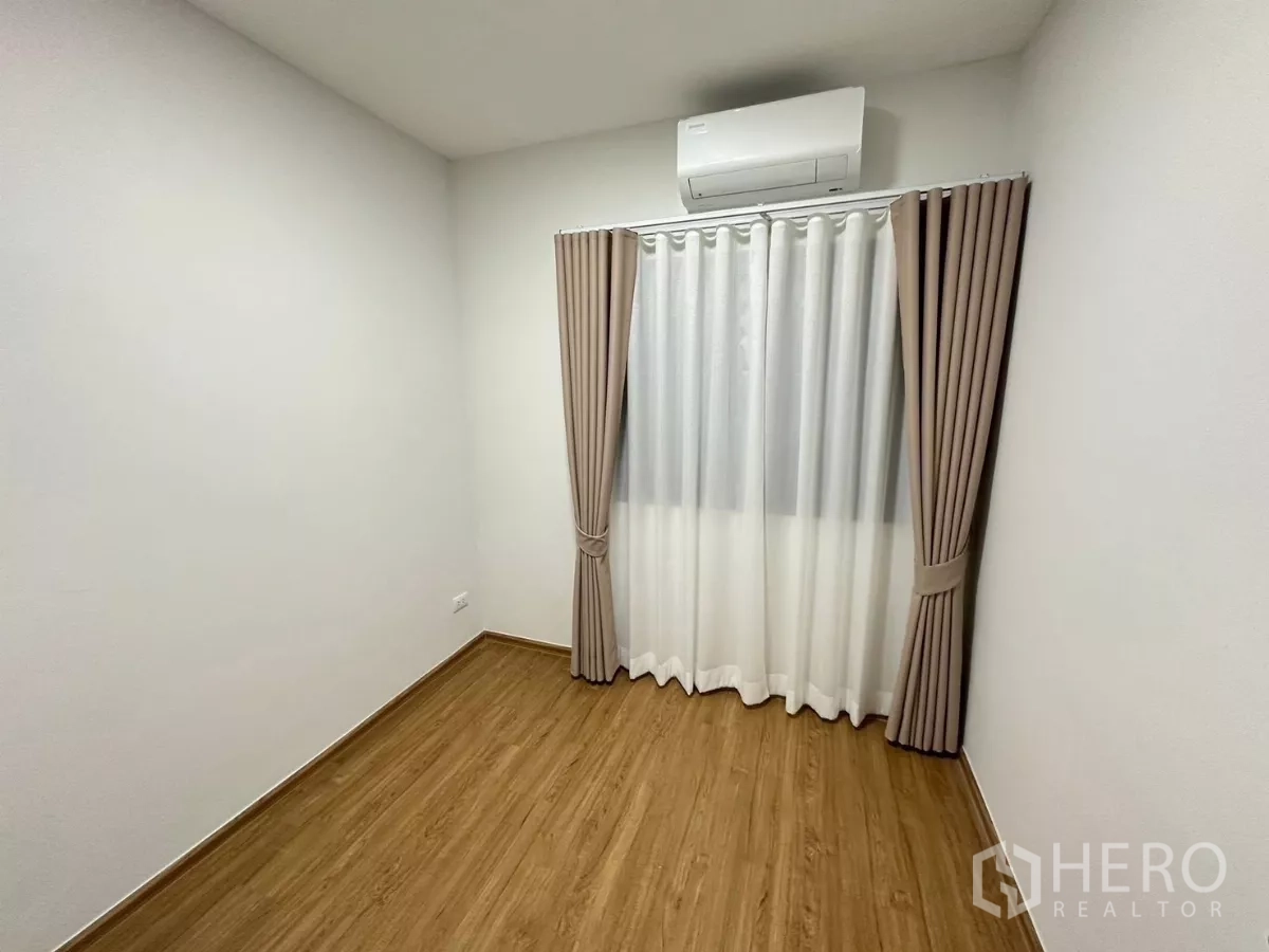Townhouse for rent in Bang Phli, Samut Prakan - Empty bedroom with air‑conditioning, curtains and wood‑look flooring.