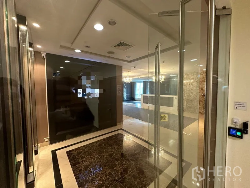 สำนักงาน ให้เช่า - ทางเข้าแบบกระจกพร้อมระบบคีย์การ์ด มองเห็นเคาน์เตอร์ต้อนรับและพื้นหินอ่อน