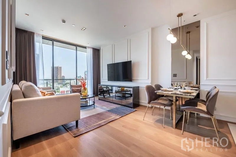 Condominium for rent in Khlong Toei, Bangkok - Open living and dining space with pendant lights and balcony outlook.