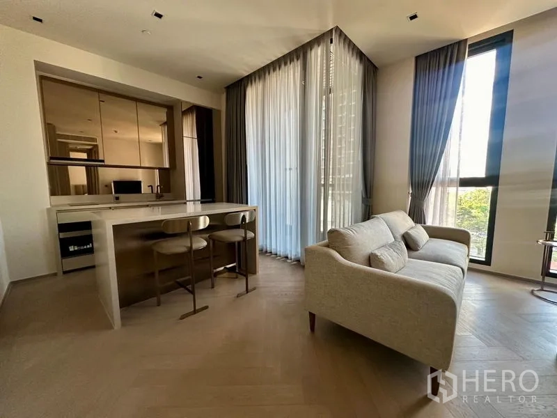 Condominium for rent - Open-plan living with kitchen island and bar stools beside tall windows.