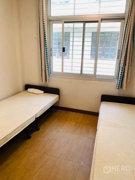 Townhouse for rent or sale in Huai Khwang, Bangkok - Guest bedroom with twin beds, sliding window and wood-style floors