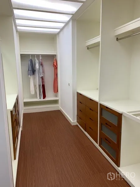 Condominium for sale in Khlong Toei, Bangkok - Walk-in closet with illuminated ceiling, custom drawers and hanging rails.