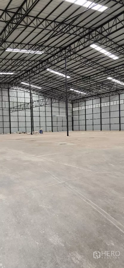 Factory for rent in Mueang Samut Sakhon, Samut Sakhon - Open-plan warehouse interior with reinforced concrete floor and black steel framework.