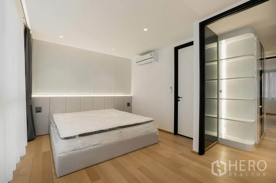 Townhouse for sale in Chatuchak, Bangkok - Secondary bedroom with minimalist bed, soft lighting and wood floors.