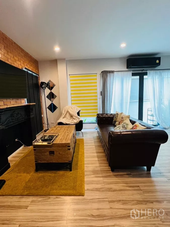 Detached House for rent in Saphan Sung, Bangkok - Spacious living area with leather sofa, sliding glass doors and wood floors.