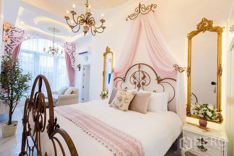 Townhouse for rent in Lat Phrao, Bangkok - Bedroom with ornate iron bed, pink canopy drapes, chandeliers and gold-framed mirrors.