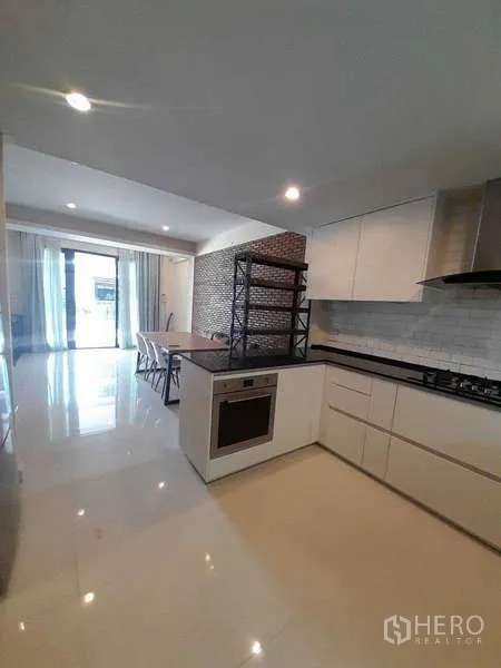 联排别墅 出租在Khlong Toei, Bangkok - 明亮U形厨房，白色橱柜、烤箱与燃气灶